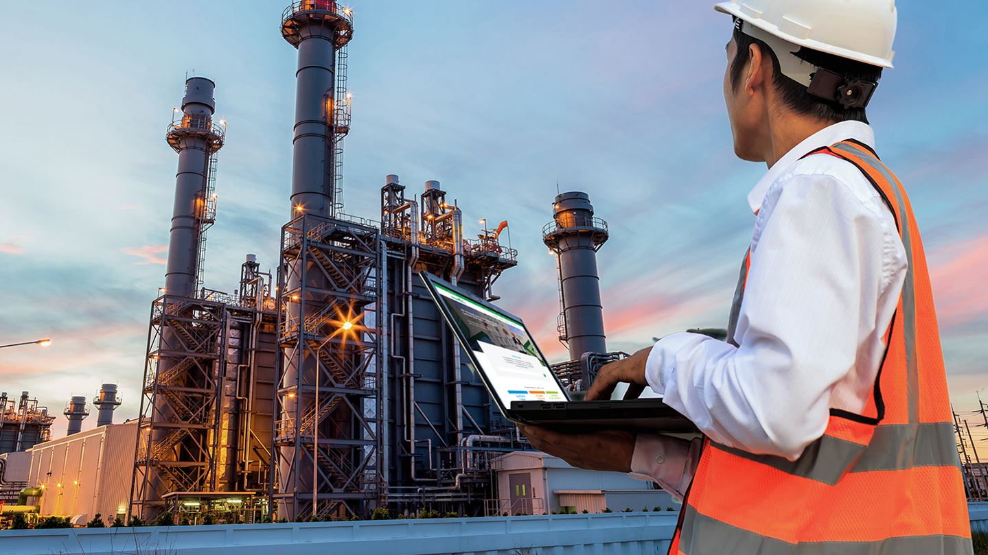 Man with laptop looking at factory